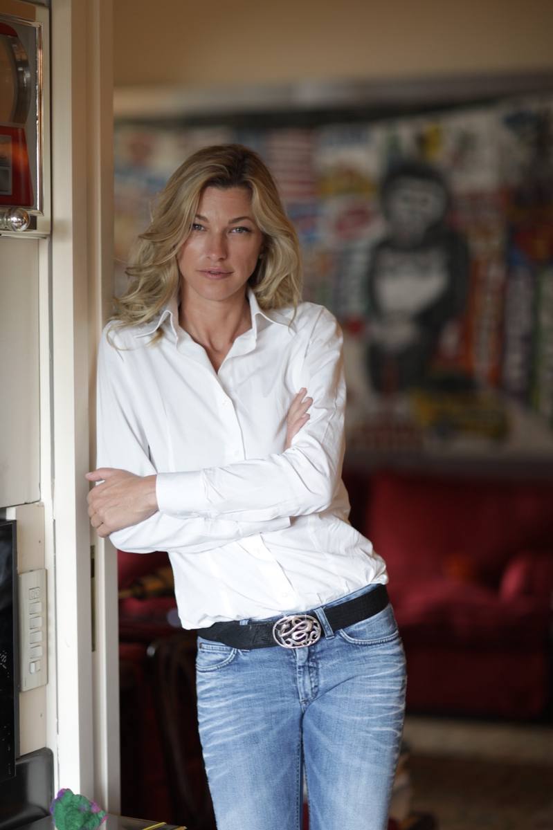 Nicole Junkermann in a white shirt, leaning in a doorway beside colourful modern art
