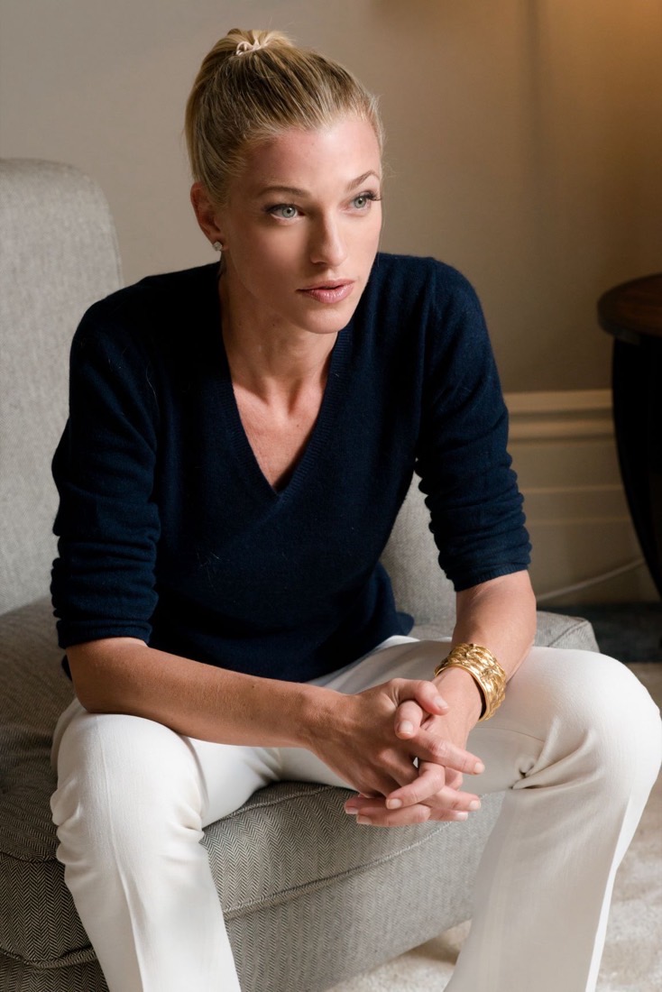 Nicole Junkermann seated in an armchair in a navy top, hands clasped, in a calm conversation